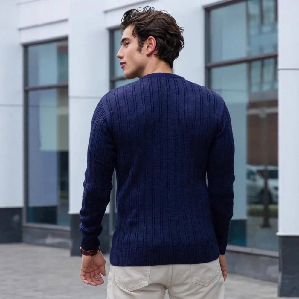 Men's navy blue cable-knit sweater styled with beige chinos – classic fall-winter pullover for men.