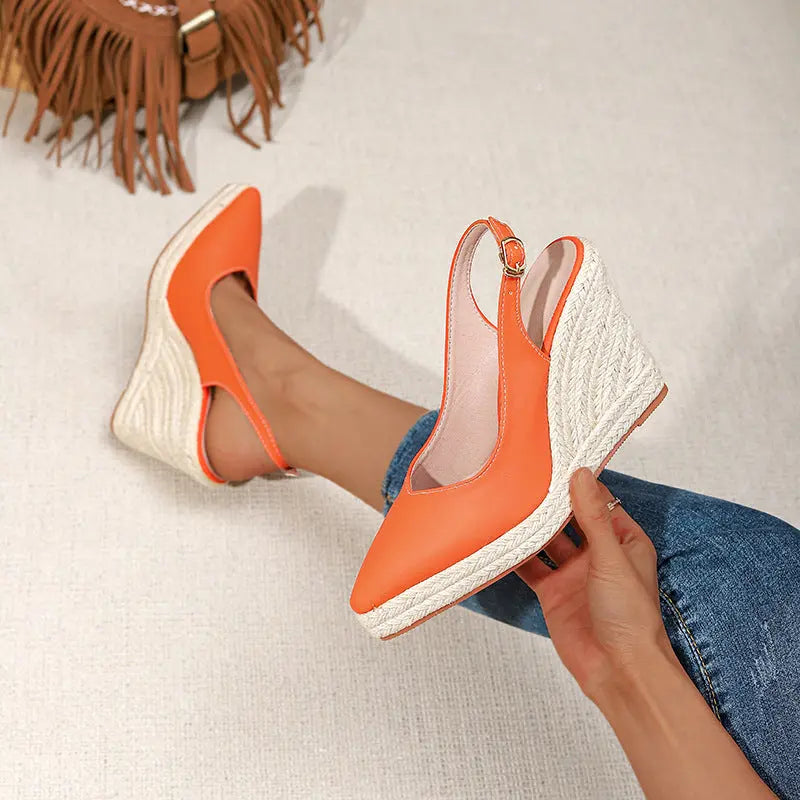 A pair of orange closed-toe high heels with buckle strap and wedge heel