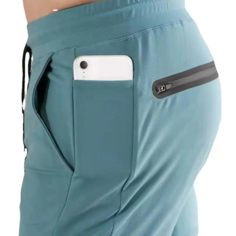 Close-up of teal blue men’s joggers with functional zip pocket – ideal for gym, running, or everyday use