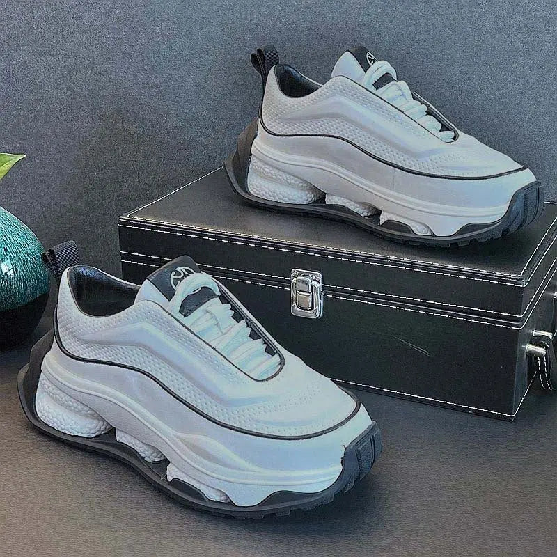 A pair of men's sneakers with a lace-up closure, featuring a white color with black accents and a thick sole.