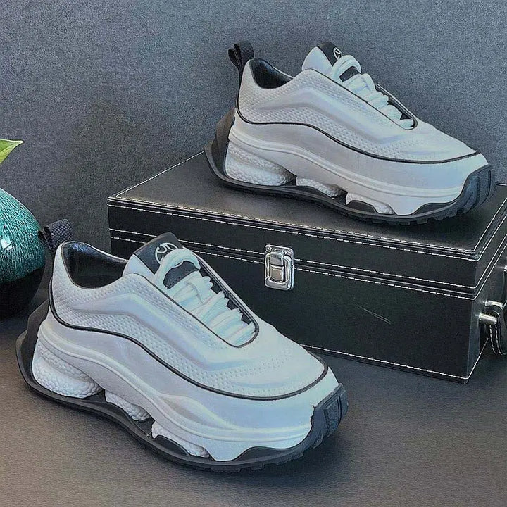 A pair of men's sneakers with a lace-up closure, featuring a white color with black accents and a thick sole.