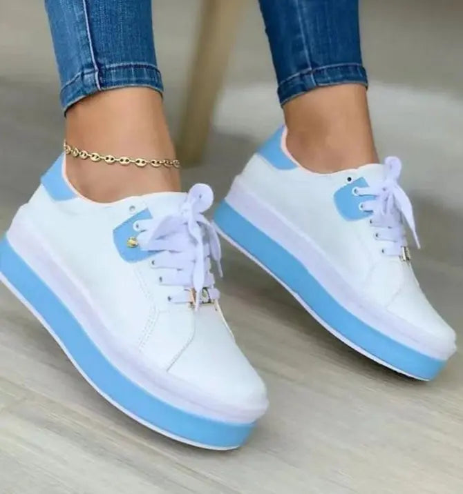 A pair of women's casual sneakers with white uppers and blue sole, laced up with white laces