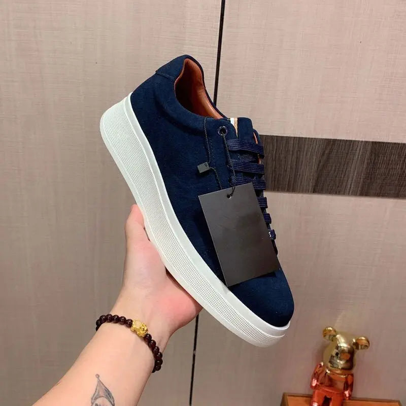 A navy blue casual sneaker held in a person's hand, featuring a white sole and lace-up closure.