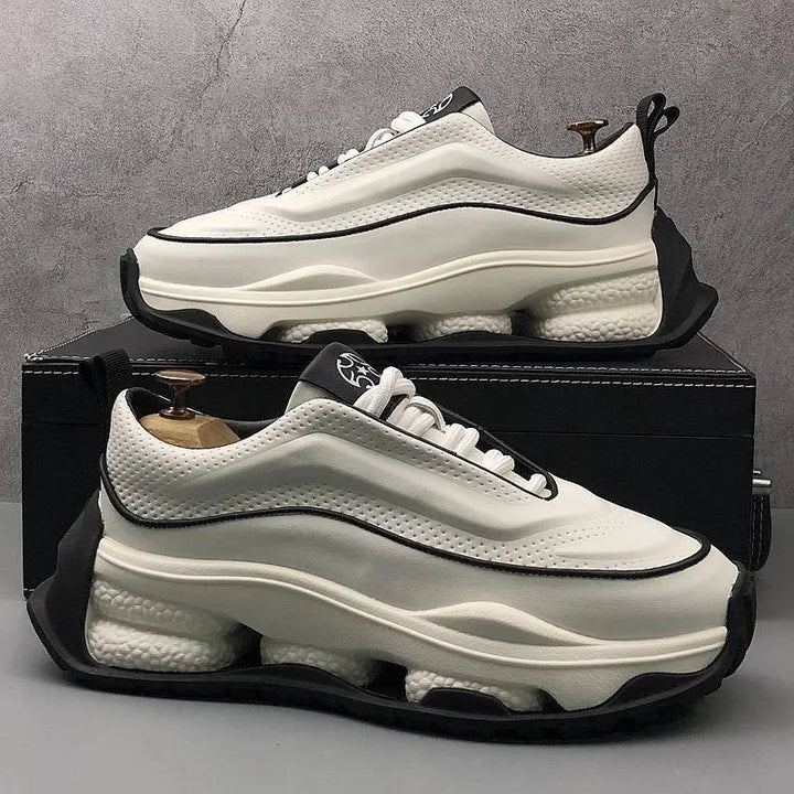 A pair of men's sneakers with a lace-up closure, featuring a white color with black accents and a thick sole.