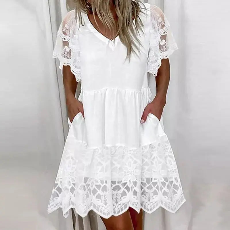 A woman wearing a white short-sleeved knee-length dress with lace detailing.