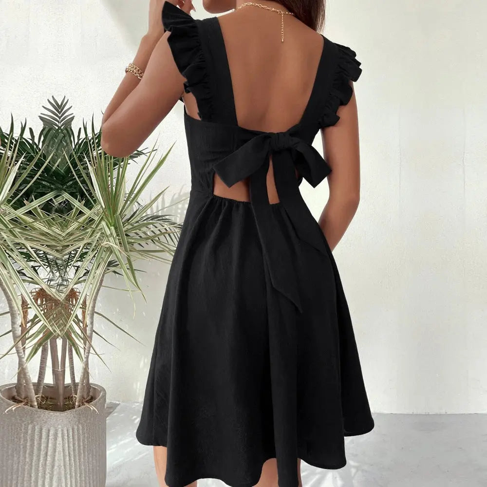 A woman wearing a black sleeveless knee-length dress with ruffled shoulder straps.