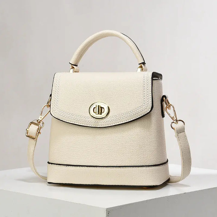 Elegant white faux leather top handle bag with gold twist-lock closure and rhinestone trim, perfect for casual or office wear.