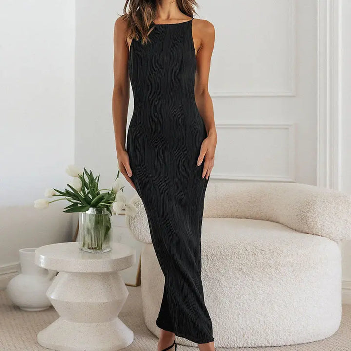 A woman wearing a black sleeveless maxi dress with a high neckline and ruffled hem.