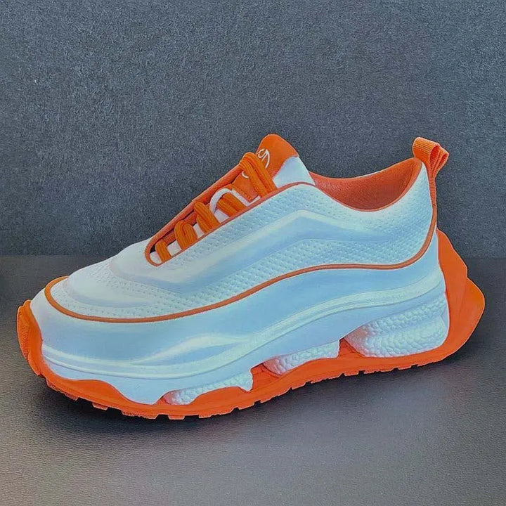 A pair of men's sneakers with a lace-up closure, featuring a white color with orange accents and a thick sole.