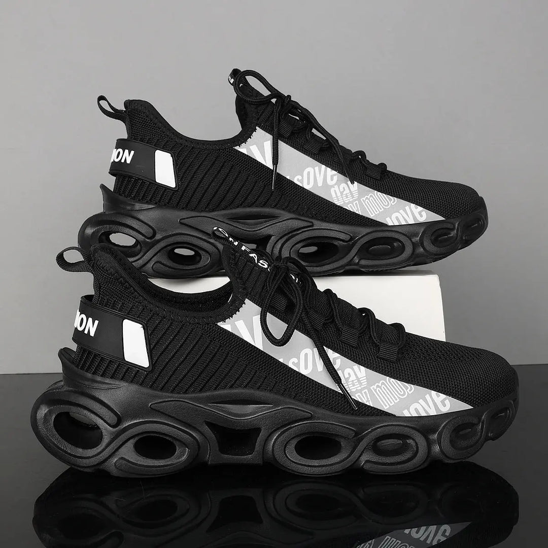 A pair of black and white sports sneakers with a breathable mesh upper and a unique sole design, displayed against a grey background.