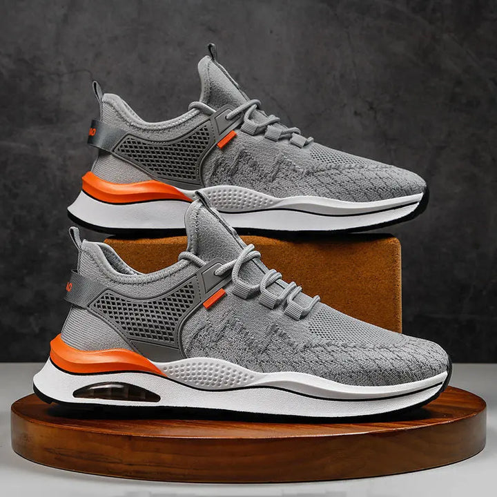 A pair of gray and white sneakers with red accents