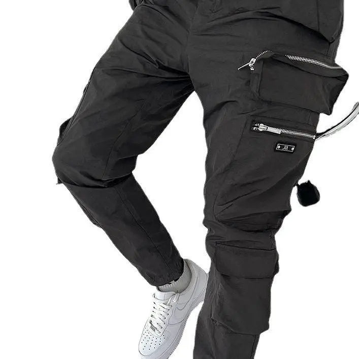 A pair of men's casual black trousers with multiple pockets and zippers, designed for versatility and functionality.