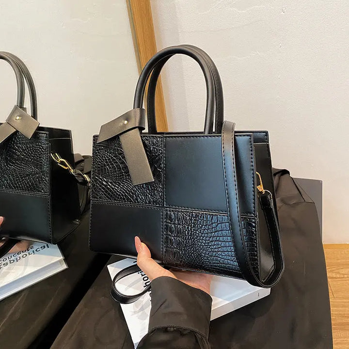 Trendy black patchwork handbag for women featuring croc-embossed leather texture and detachable shoulder strap.