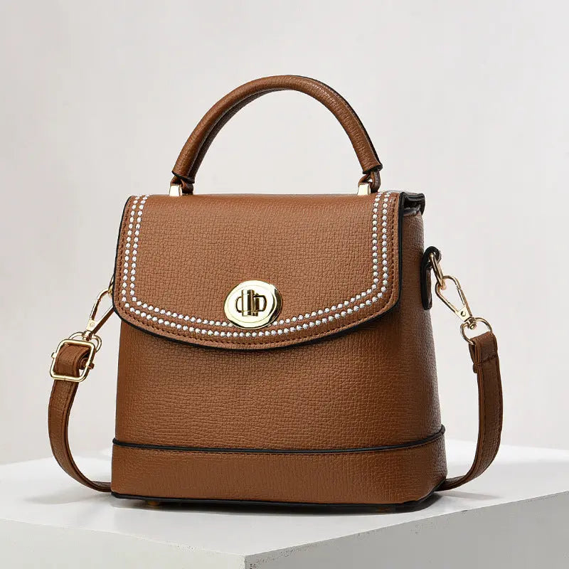 Elegant brown faux leather top handle bag with gold twist-lock closure and rhinestone trim, perfect for casual or office wear.
