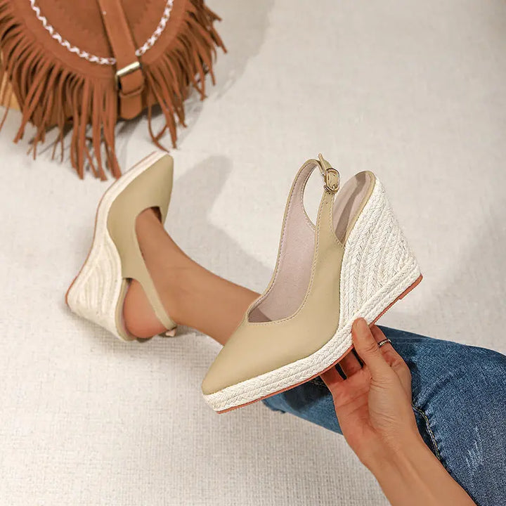 A pair of beige closed-toe high heels with buckle strap and wedge heel