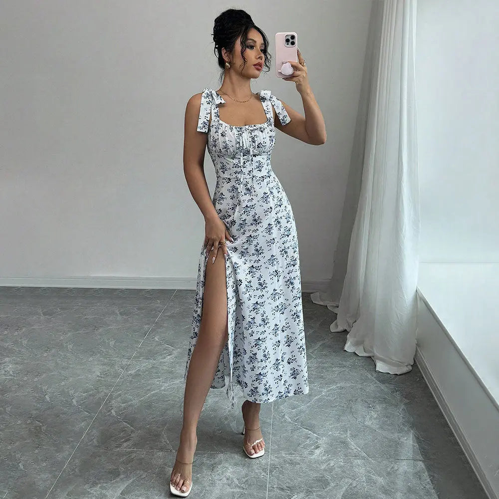 A woman modeling a floral CityChic slit dress with a square neckline and sleeveless design, featuring a side slit.