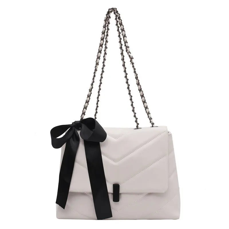 Stylish white quilted shoulder bag for women with chain strap and decorative bow, ideal for evening or date night looks.
