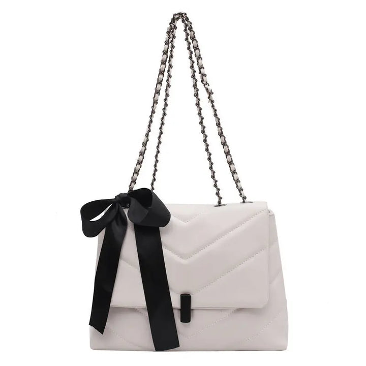 Stylish white quilted shoulder bag for women with chain strap and decorative bow, ideal for evening or date night looks.