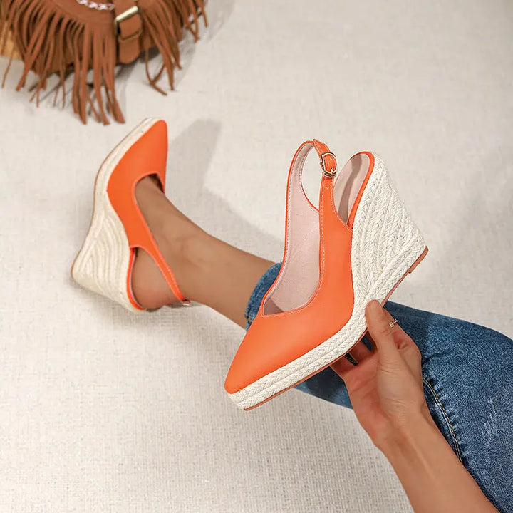 A pair of orange closed-toe high heels with buckle strap and wedge heel
