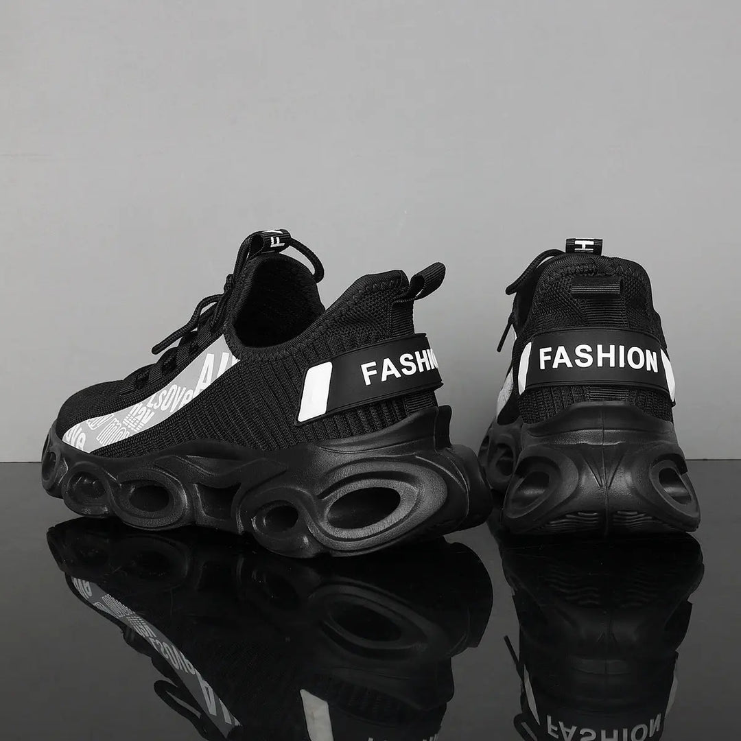 A pair of black and white sports sneakers with a breathable mesh upper and a unique sole design, displayed against a grey background.