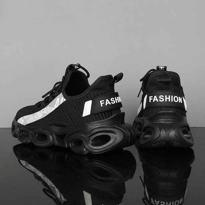 A pair of black and white sports sneakers with a breathable mesh upper and a unique sole design, displayed against a grey background.