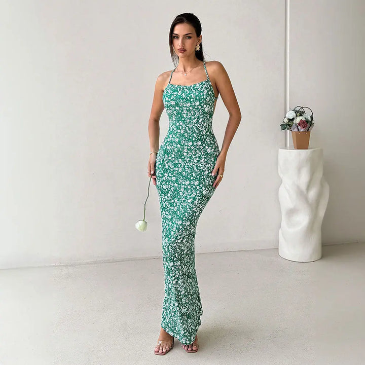A woman wearing a sleeveless, green floral print, maxi dress with spaghetti straps