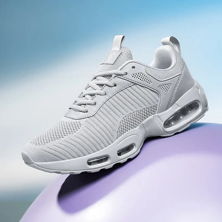 Gray athletic shoe with air cushioning on a gradient background