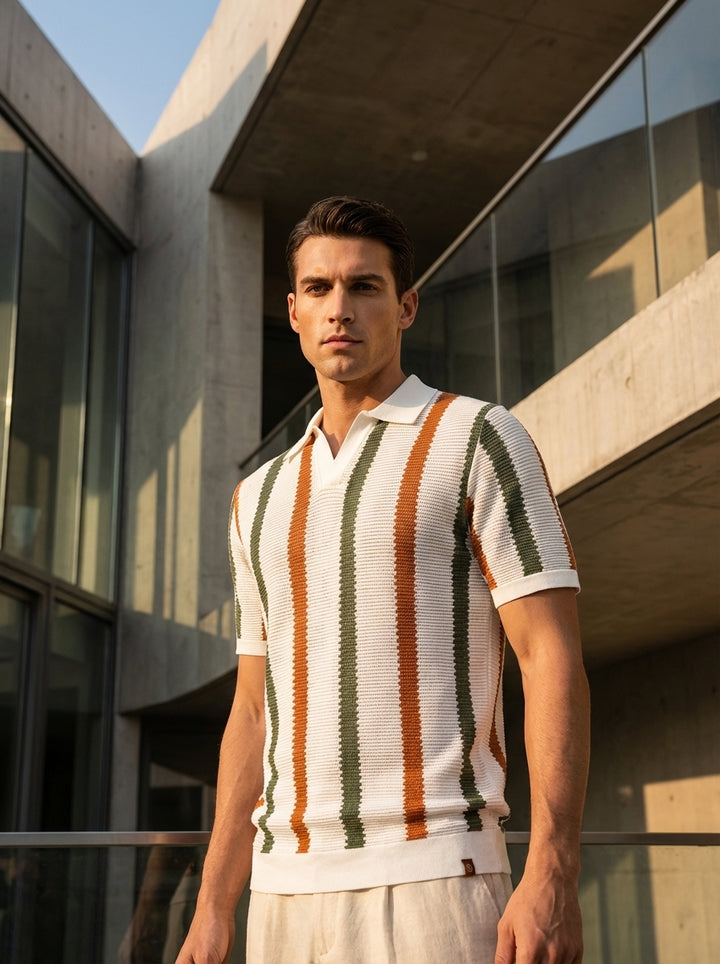 Man wearing a striped polo shirt standing in front of a modern building.